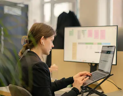 Person working at a laptop with a research board on the monitor behind