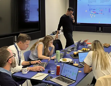 Team mapping customer journeys on a large screen during a workshop around a meeting table
