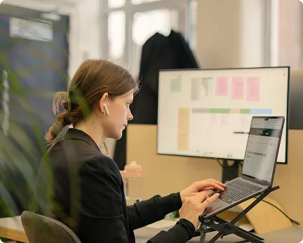 Person working at a laptop with a research board on the monitor behind