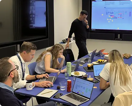 Team mapping customer journeys on a large screen during a workshop around a meeting table