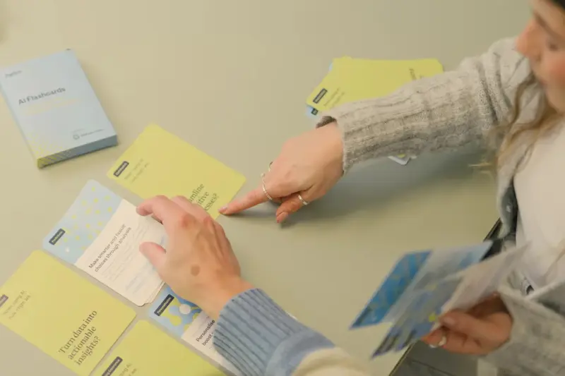 Two people working through Pattrn AI flashcards spread across a table