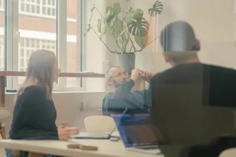 Team meeting around a table, seen through a glass partition