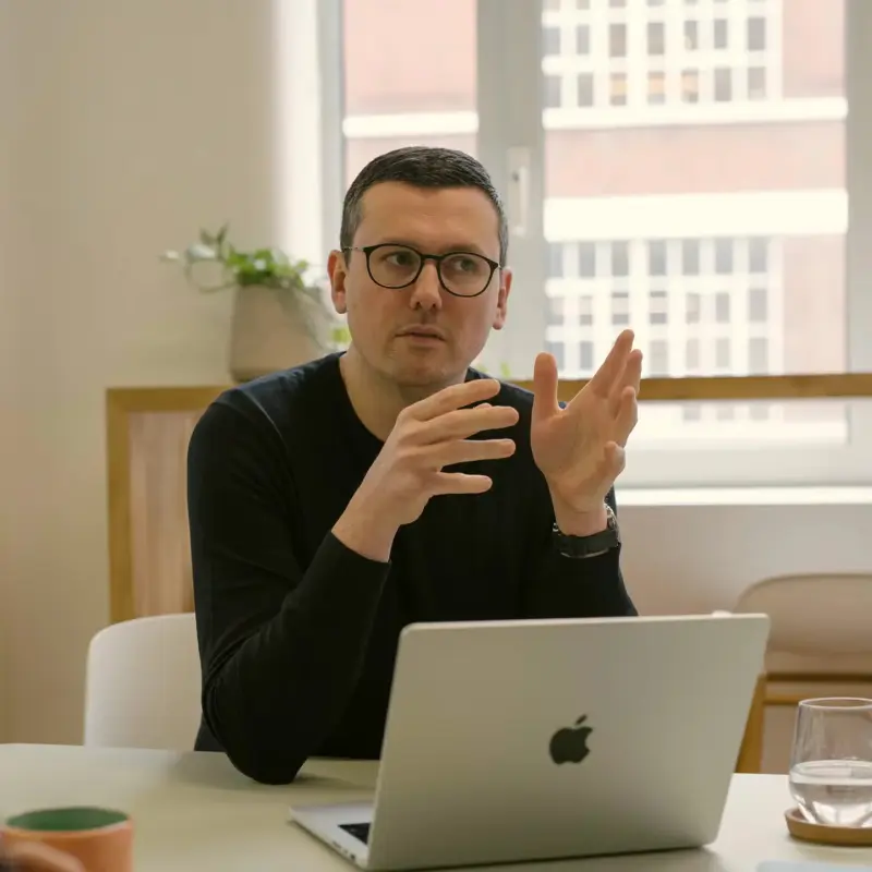 Team member in glasses explaining an idea at a laptop