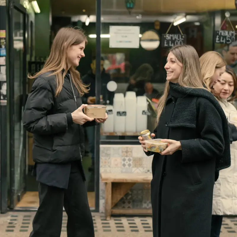 Colleagues chatting with takeaway food outside a market café