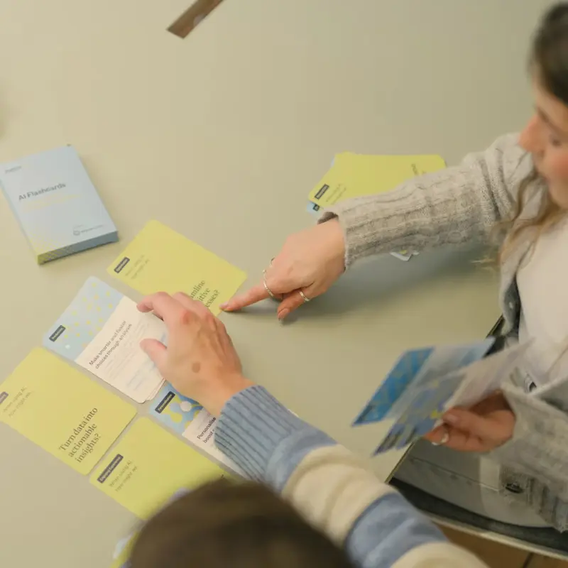 Two people working through Pattrn AI flashcards spread across a table