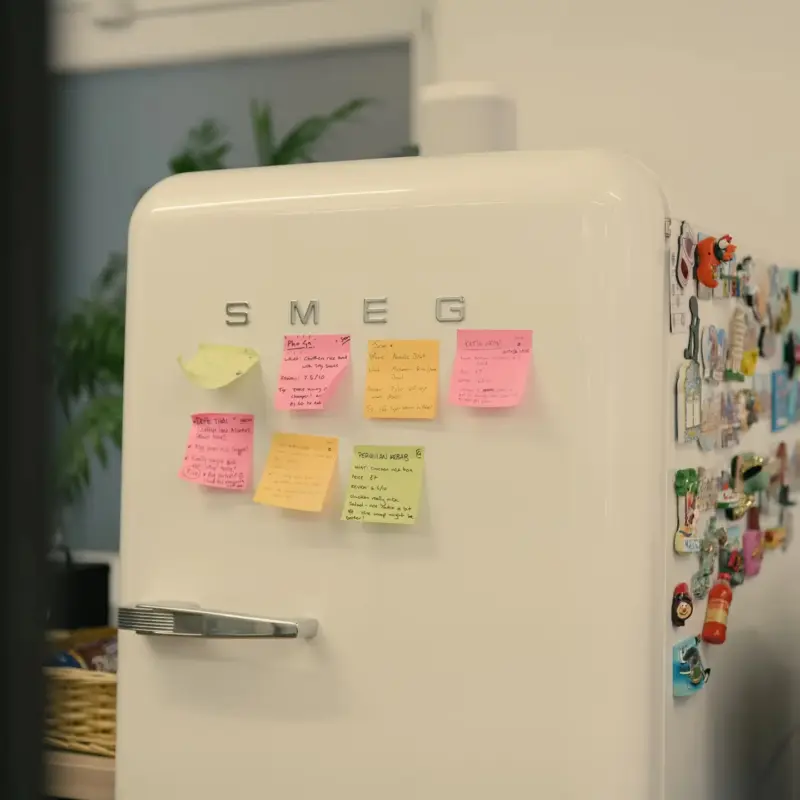 Sticky notes and magnets covering a cream Smeg fridge in the studio