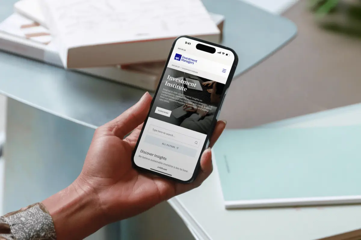 Hand holding a phone showing the AXA IM Investment Institute page