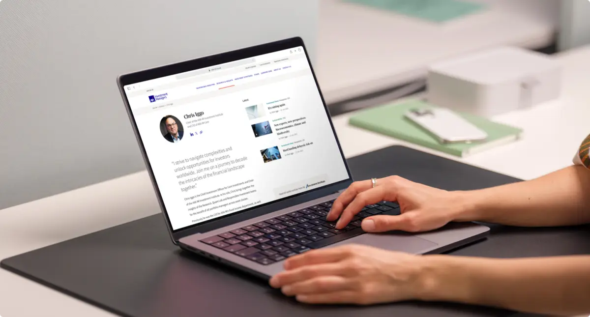Person using a laptop showing an AXA IM author page for Chris Iggo