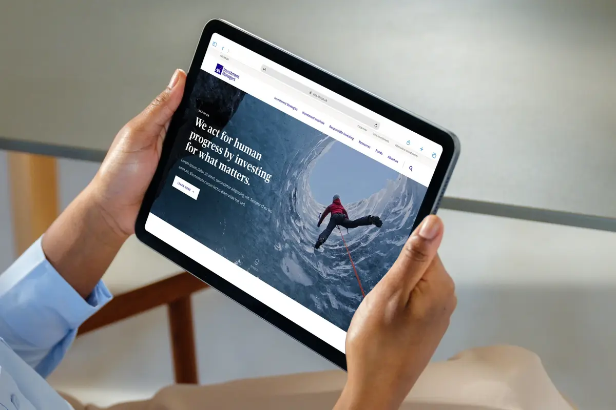 Hands holding a tablet showing the AXA IM homepage, 'We act for human progress by investing for what matters'