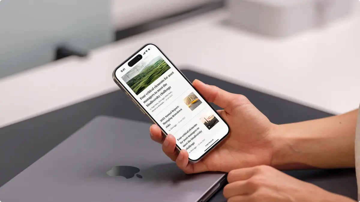 Hand holding a phone showing AXA IM insight articles on the mobile site