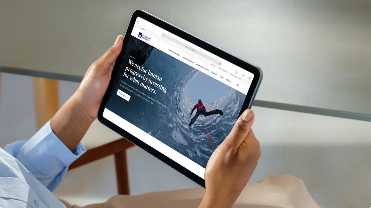 Hands holding a tablet showing the AXA IM homepage, 'We act for human progress by investing for what matters'