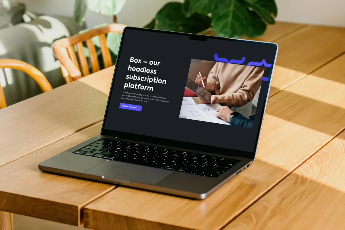 Laptop on a wooden table showing the Bento homepage, 'Box – our headless subscription platform'