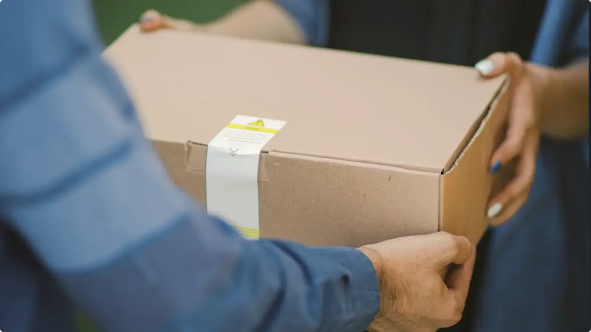 Cardboard parcel being handed from one person to another