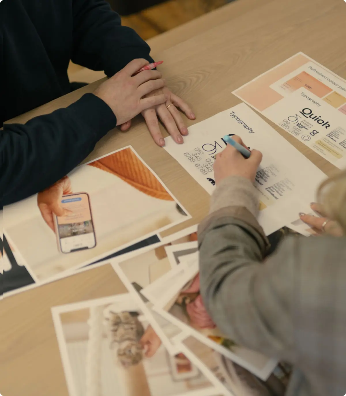 Hands annotating printed Blink typography and design concepts on a table
