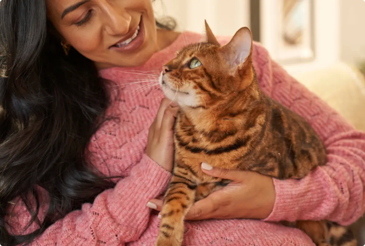 Smiling woman cuddling a tabby cat