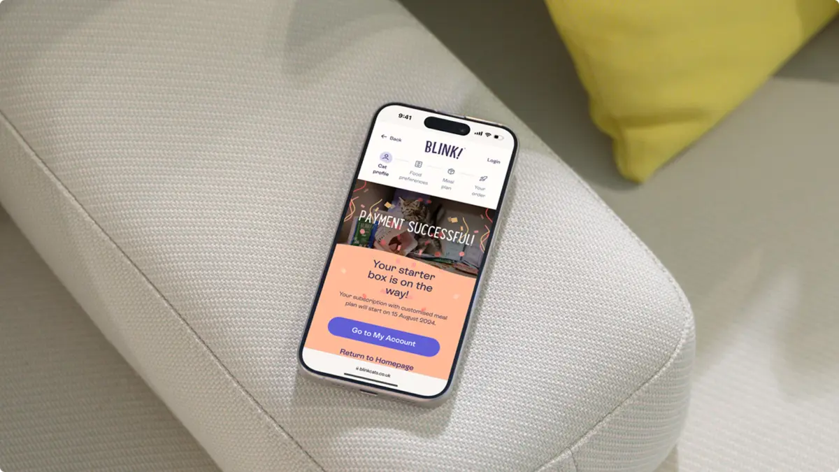 Phone on a sofa showing Blink's confirmation screen, 'Your starter box is on the way!'