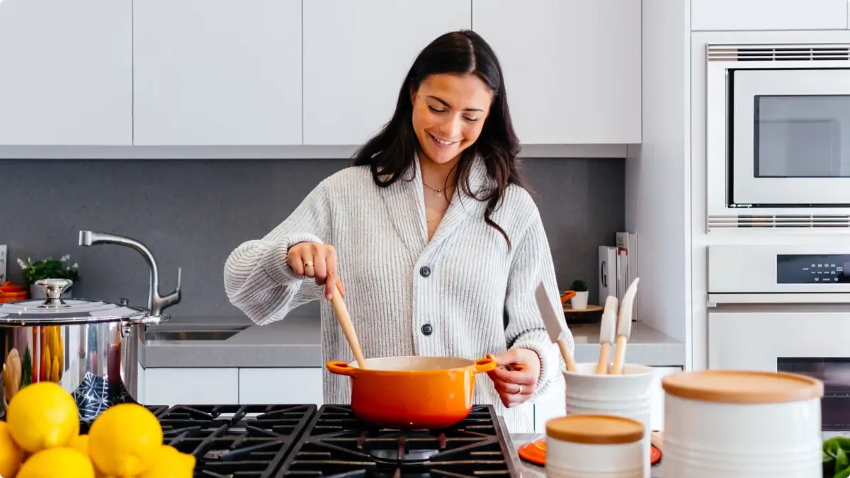 Woman stirring a pot on a kitchen hob
