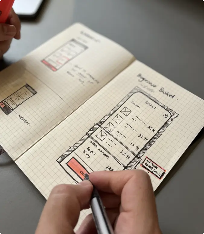 Hand sketching a basket screen wireframe in a notebook