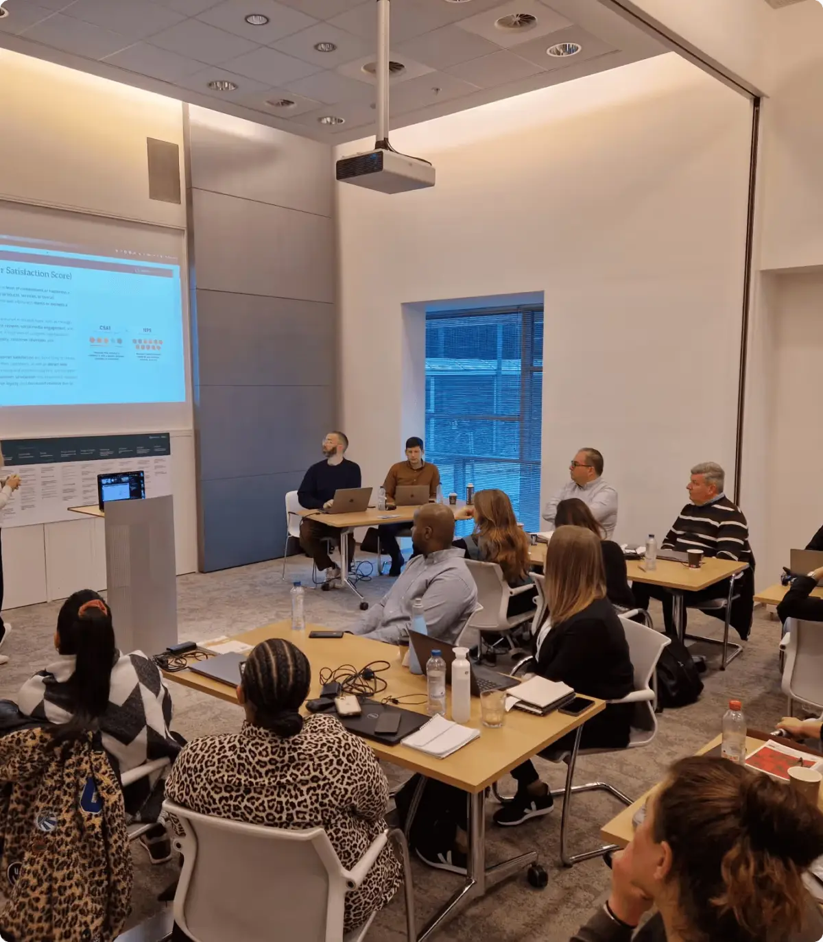 Workshop with participants seated at tables facing a presentation screen