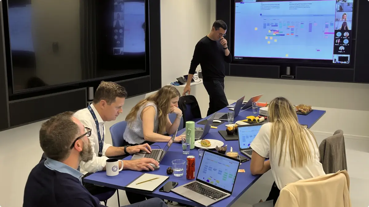 Team mapping customer journeys on a large screen during a workshop around a meeting table