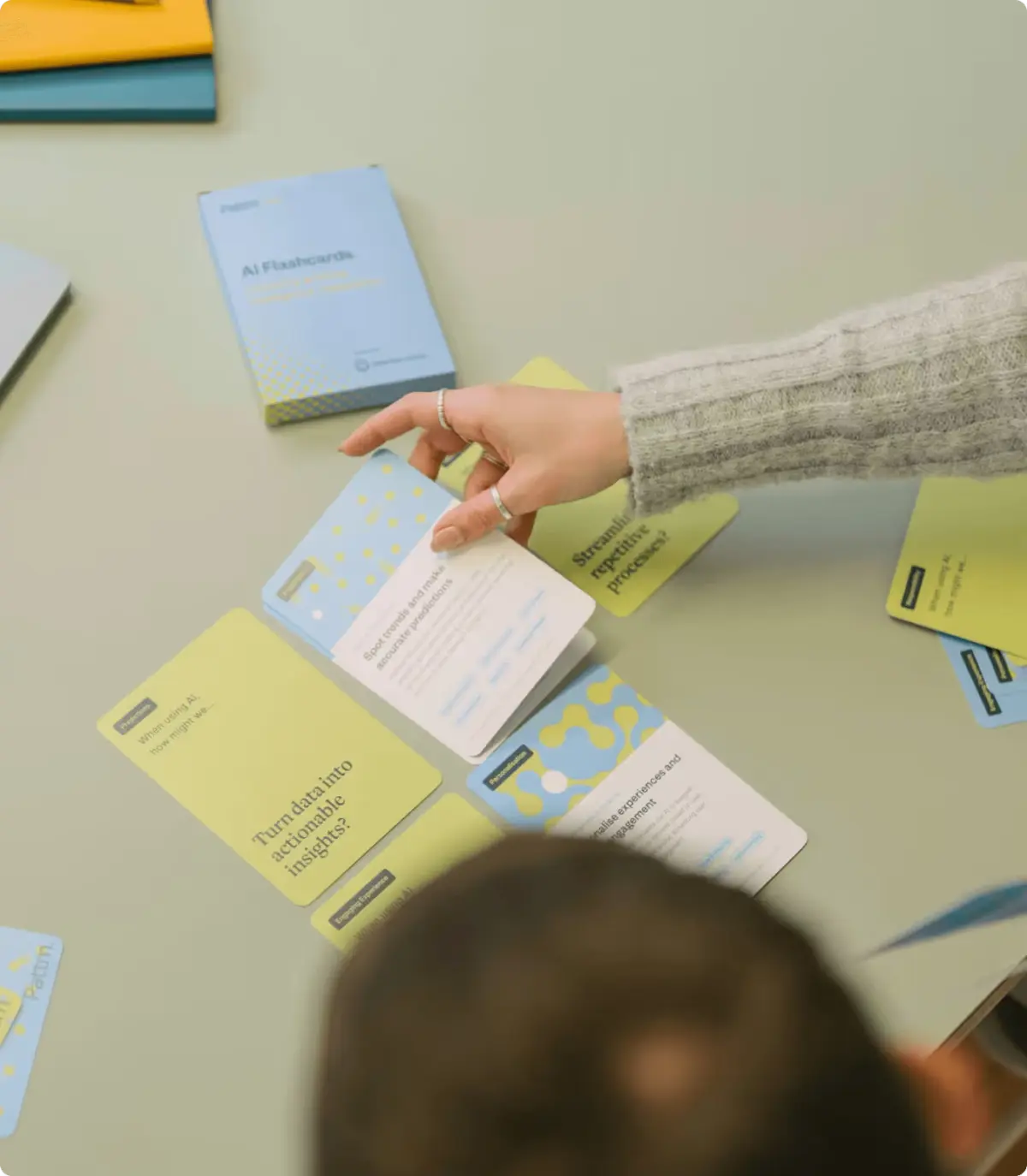 Hand picking up one of the AI flashcards spread across a table