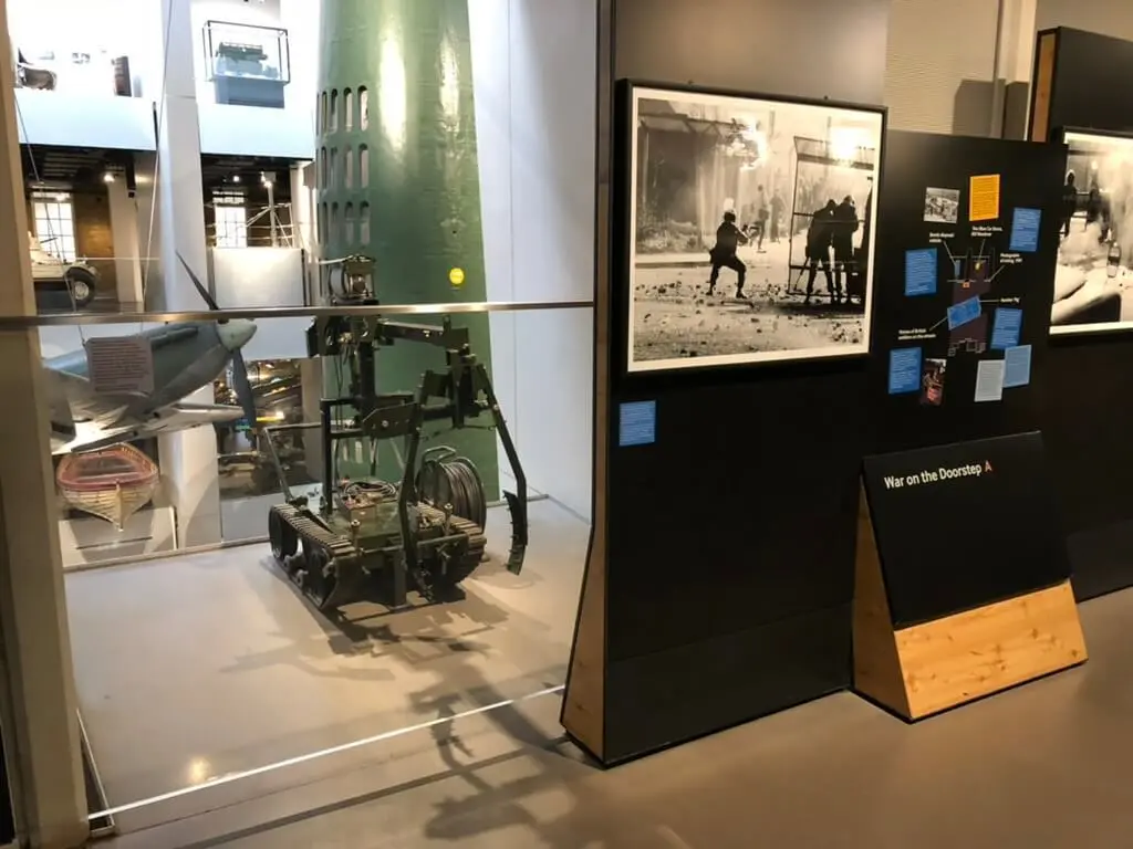 Museum gallery display beside a robotic vehicle, its information panel covered in sticky notes