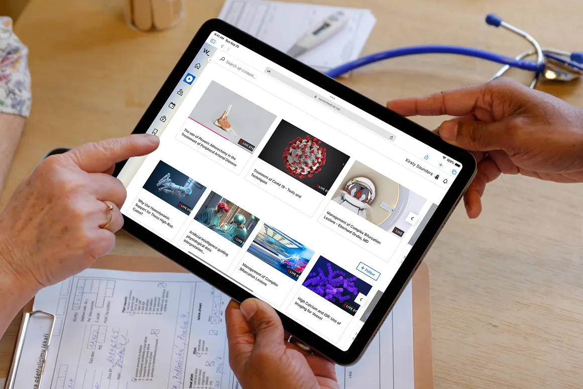 Hands holding a tablet showing Wondr's medical video library, with a stethoscope on the desk