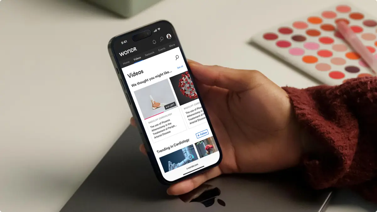 Hand holding a phone showing the Wondr videos screen