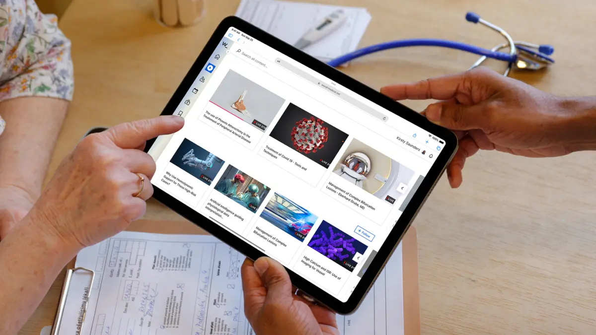 Hands holding a tablet showing Wondr's medical video library, with a stethoscope on the desk